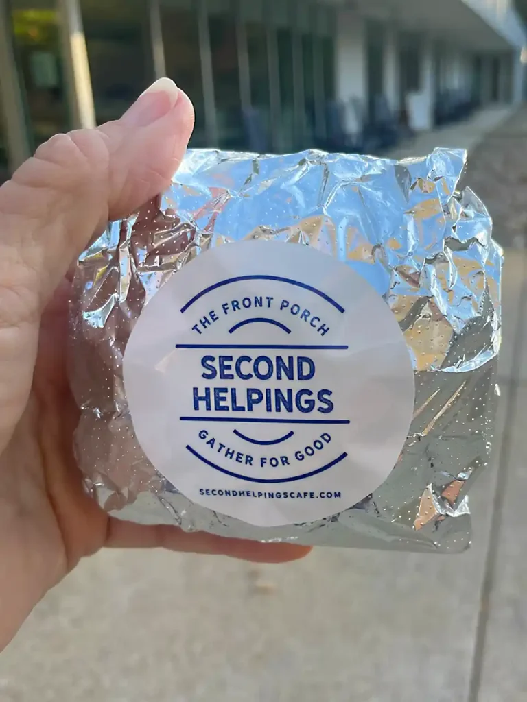 Foil-wrapped breakfast sandwich with a Second Helpings Café branded sticker
