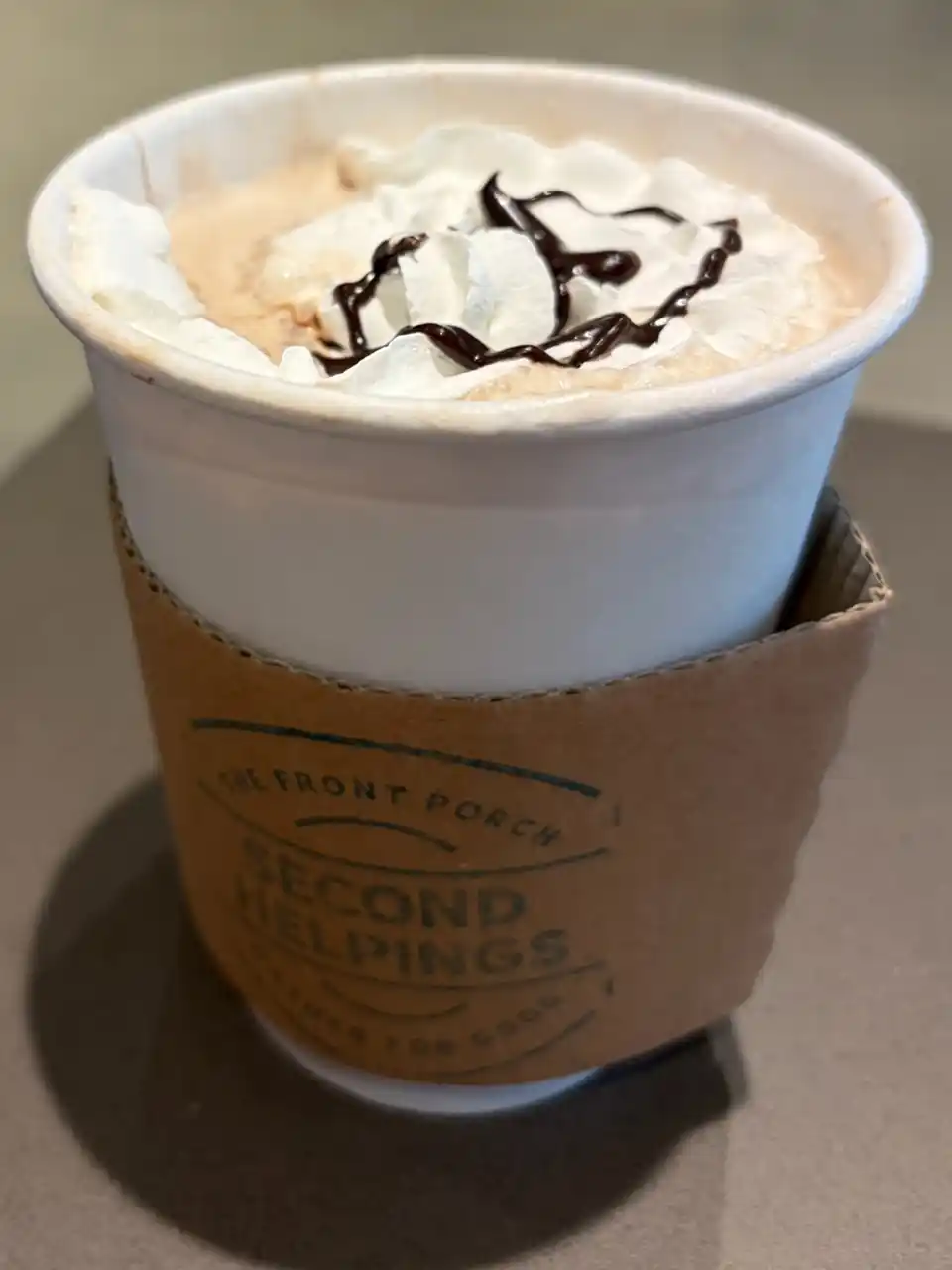 Coffee drink in a to-go cup with whipped cream and caramel drizzle