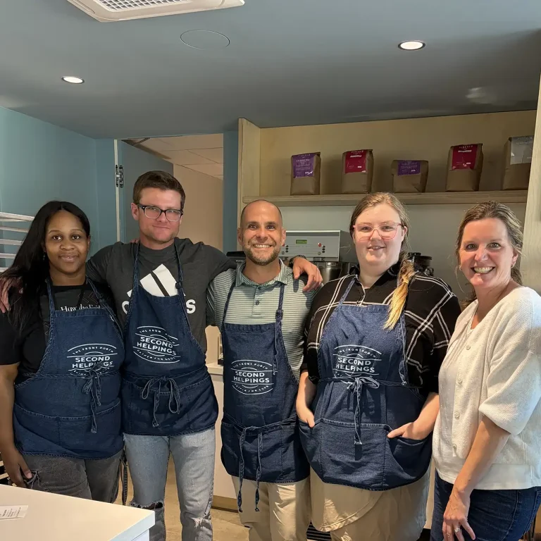Lauren Young with the Second Helpings Café team wearing branded aprons in the Memphis kitchen