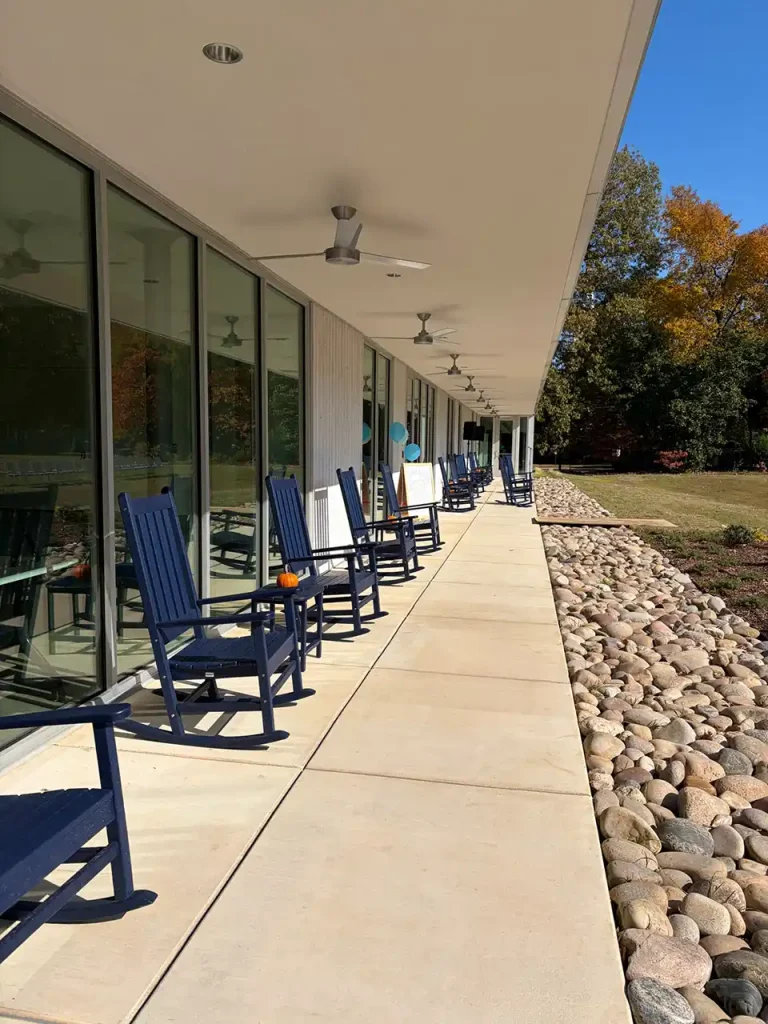 Blue rocking chairs on the covered front porch at Second Helpings Café community gathering space