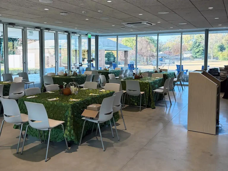 Event space at The Front Porch Memphis with floor-to-ceiling glass windows, fully set with dinner tables and chairs for a formal gathering