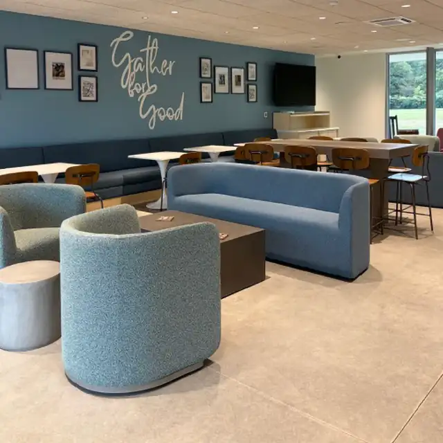 Second Helpings Café seating area with couches, chairs, and blue walls with Gather For Good lettering