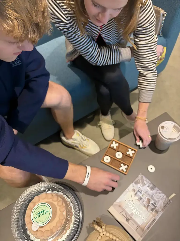 Young adults playing tic-tac-toe game with cookies and treats at Second Helpings Café